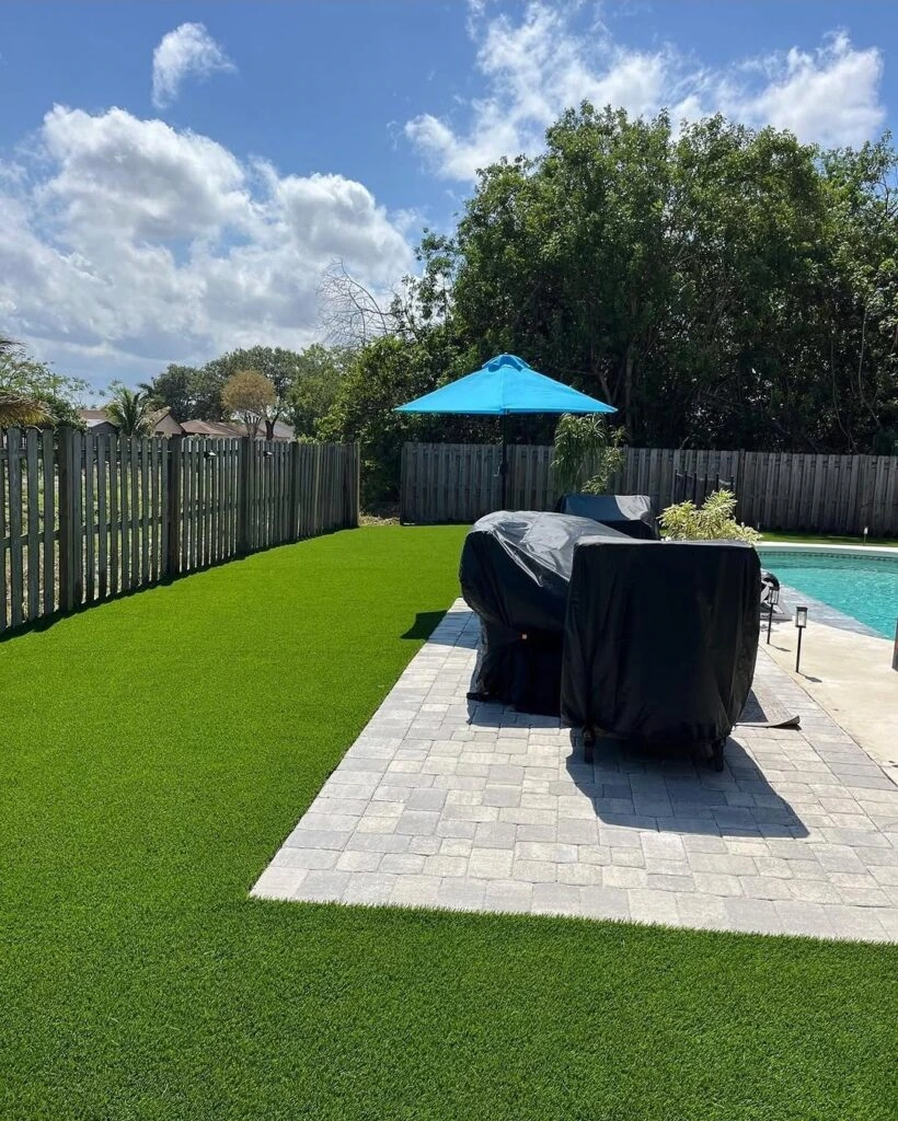 Artificial turf and paver pool deck backyard with outdoor grill area