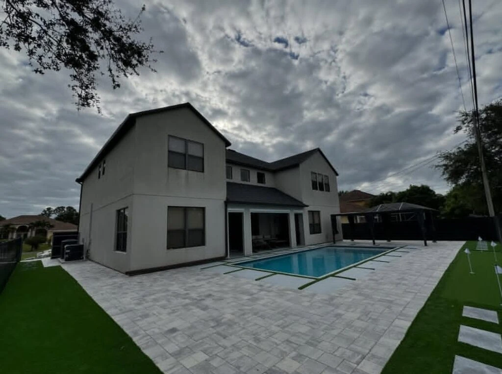Backyard artificial turf putting green with paver pool deck installation