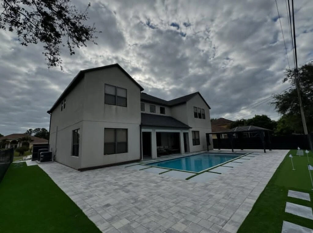 Backyard artificial turf putting green with paver pool deck installation