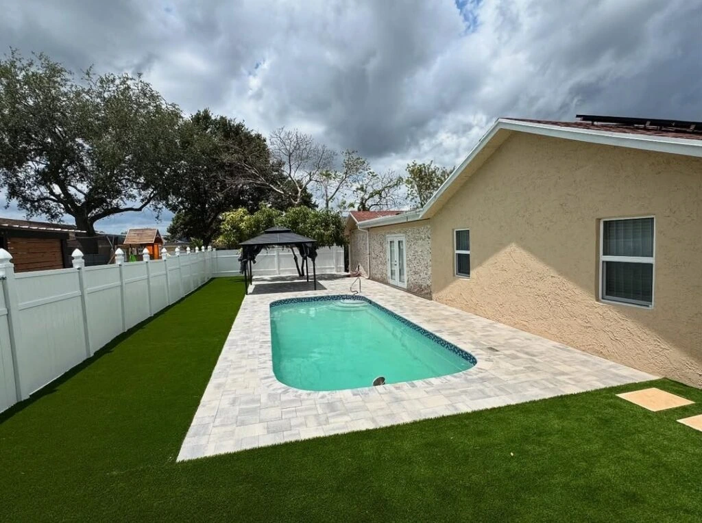 Artificial turf and paver pool deck backyard installation