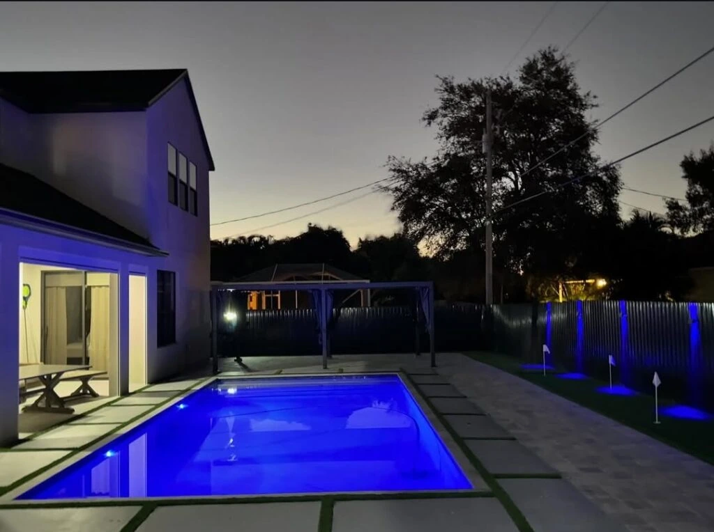 Artificial turf and paver pool deck installation with evening lighting
