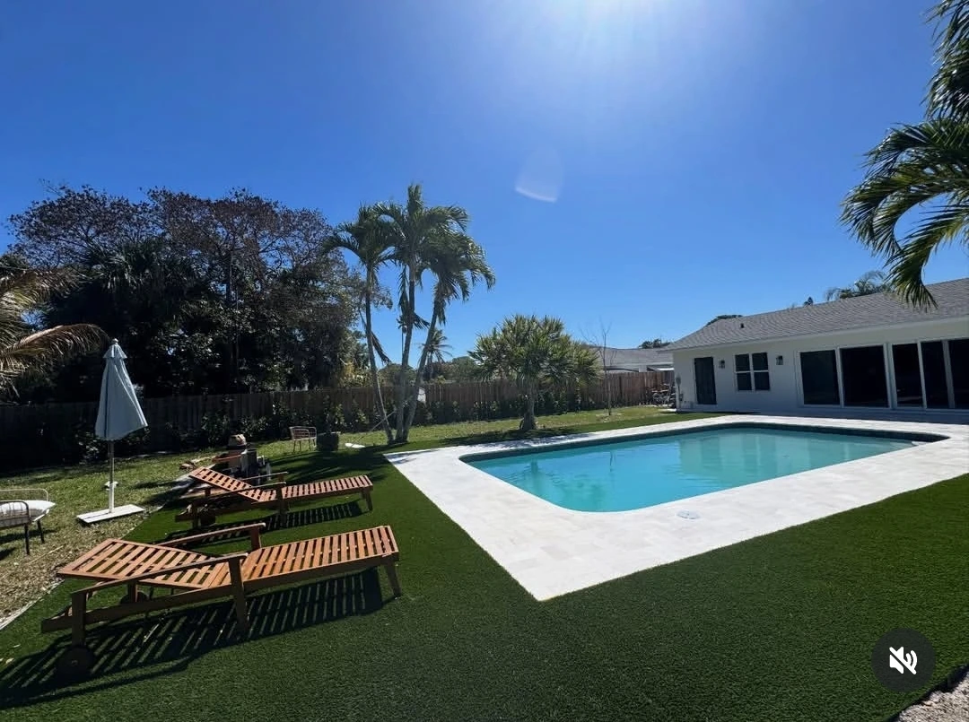Pool paver deck with artificial turf and lounge chairs