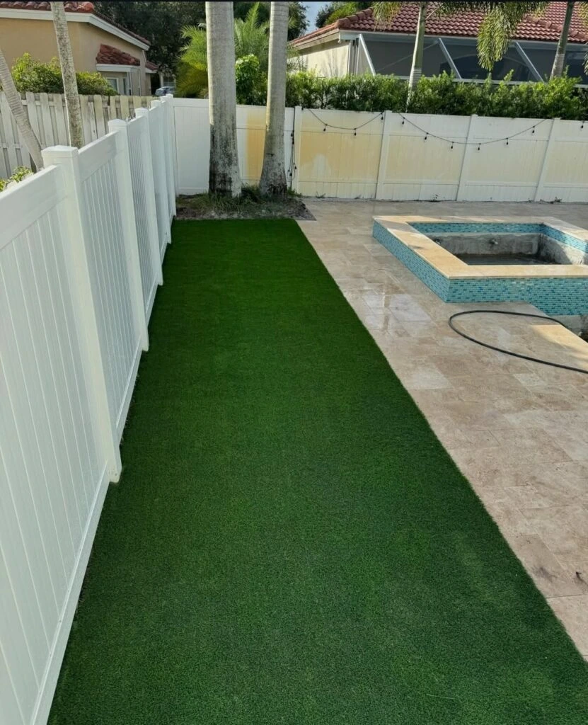 Artificial turf strip beside pool spa with paver deck