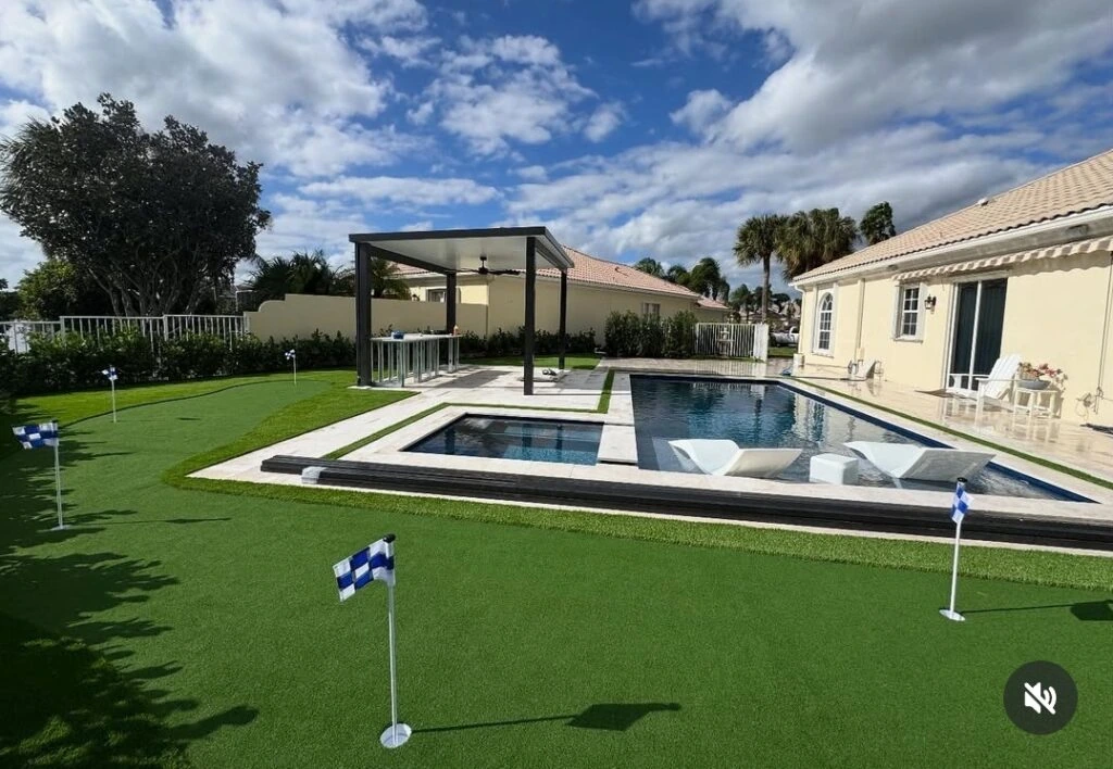 Luxury backyard with artificial turf putting green pool and paver deck