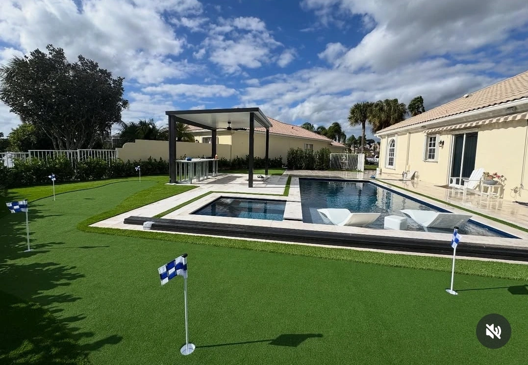 Luxury backyard with artificial turf putting green pool and paver deck