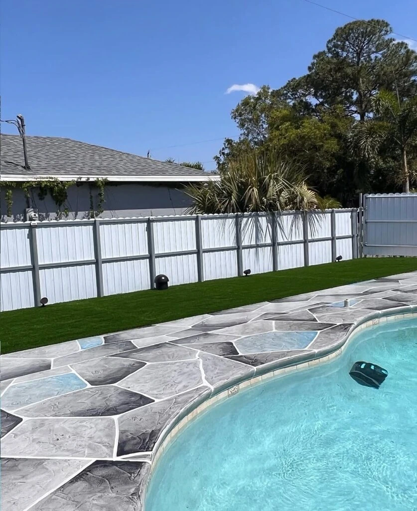 Artificial turf installation beside stamped paver pool deck